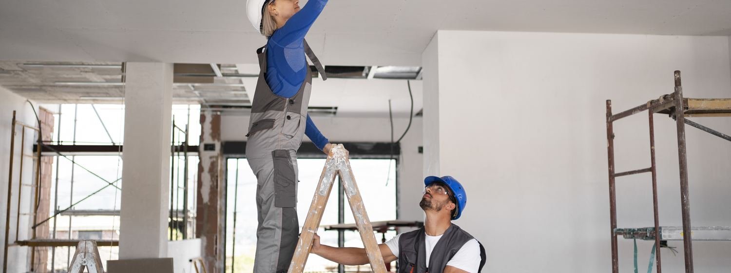 Two workers finishing a drywall ceiling together